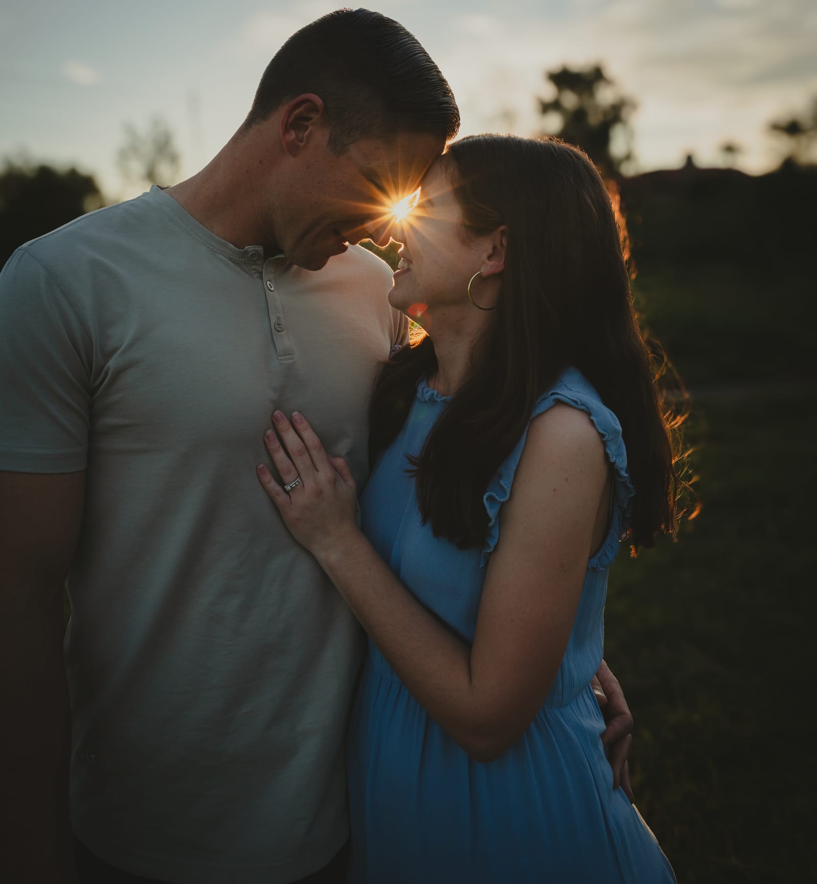 Couple forehead to forehead with a sun star between them at golden hour, Phoenix, Arizona