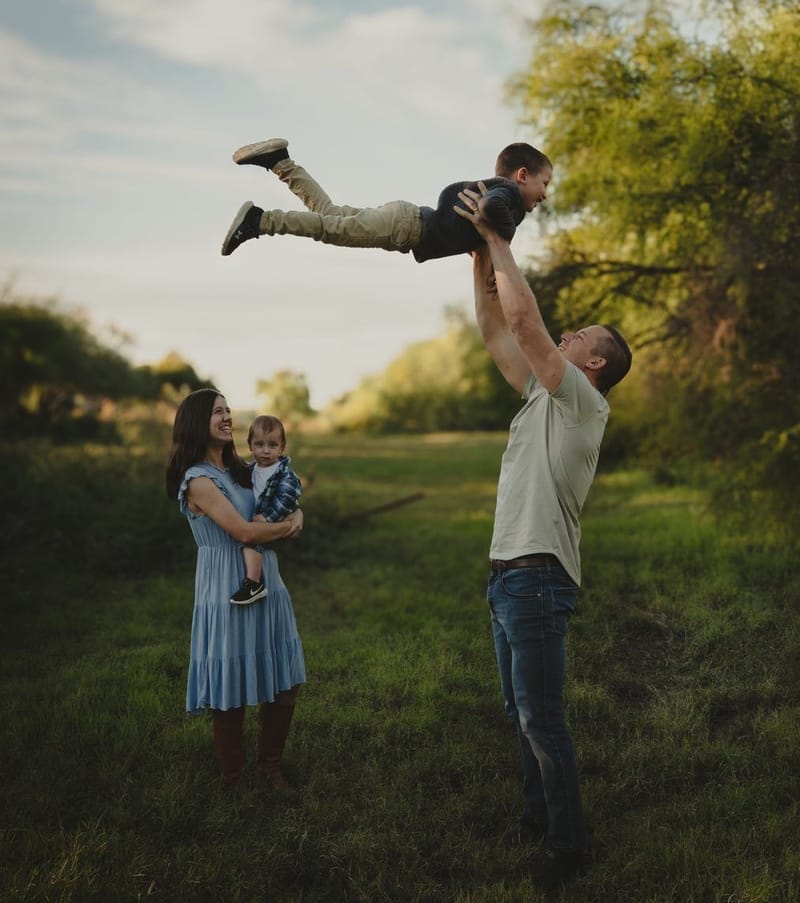 Dad flying his child airplane-style in a golden field, family photography in Tempe, Arizona