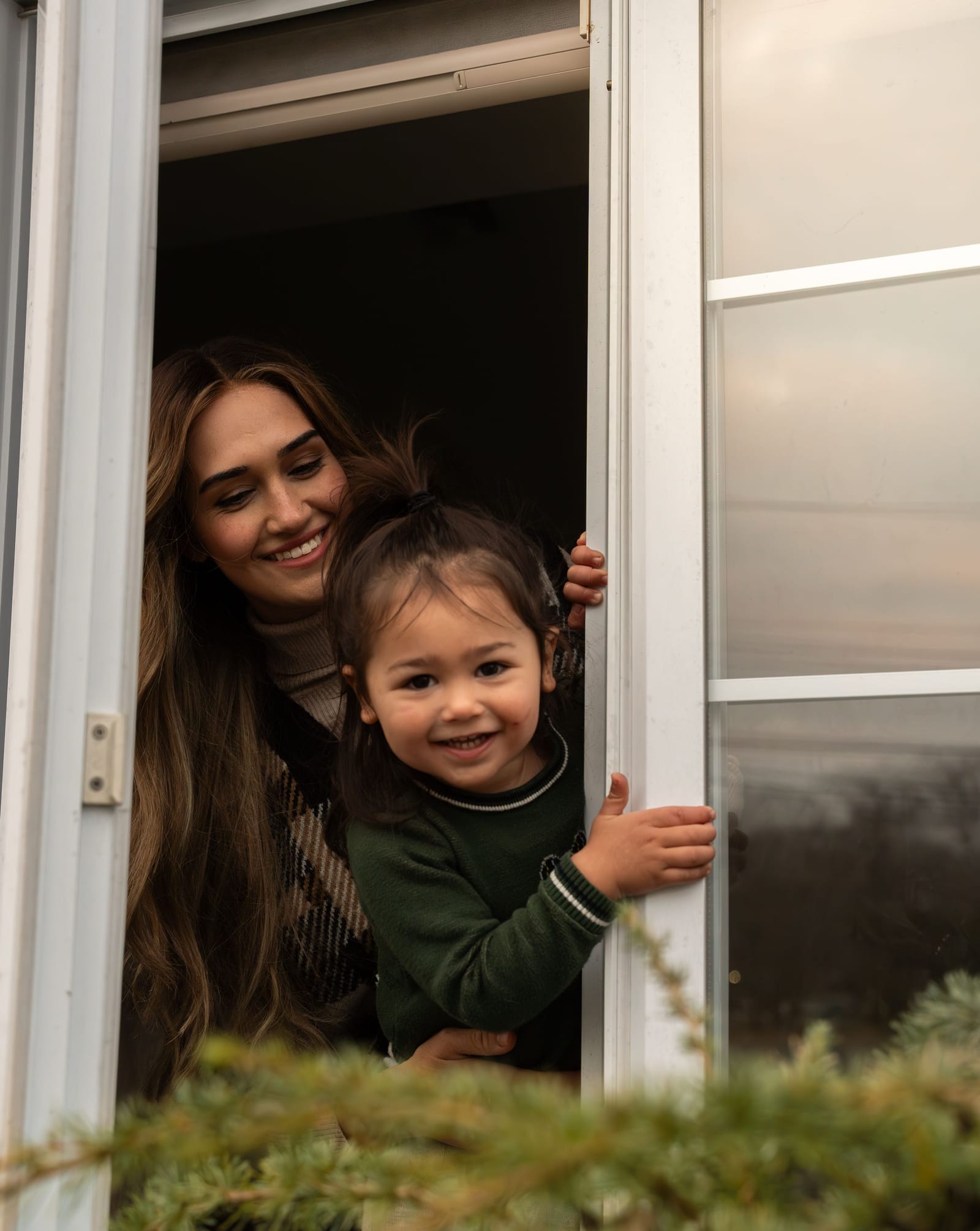 Family laughing while peeking through a doorway, candid in-home session, Phoenix, Arizona