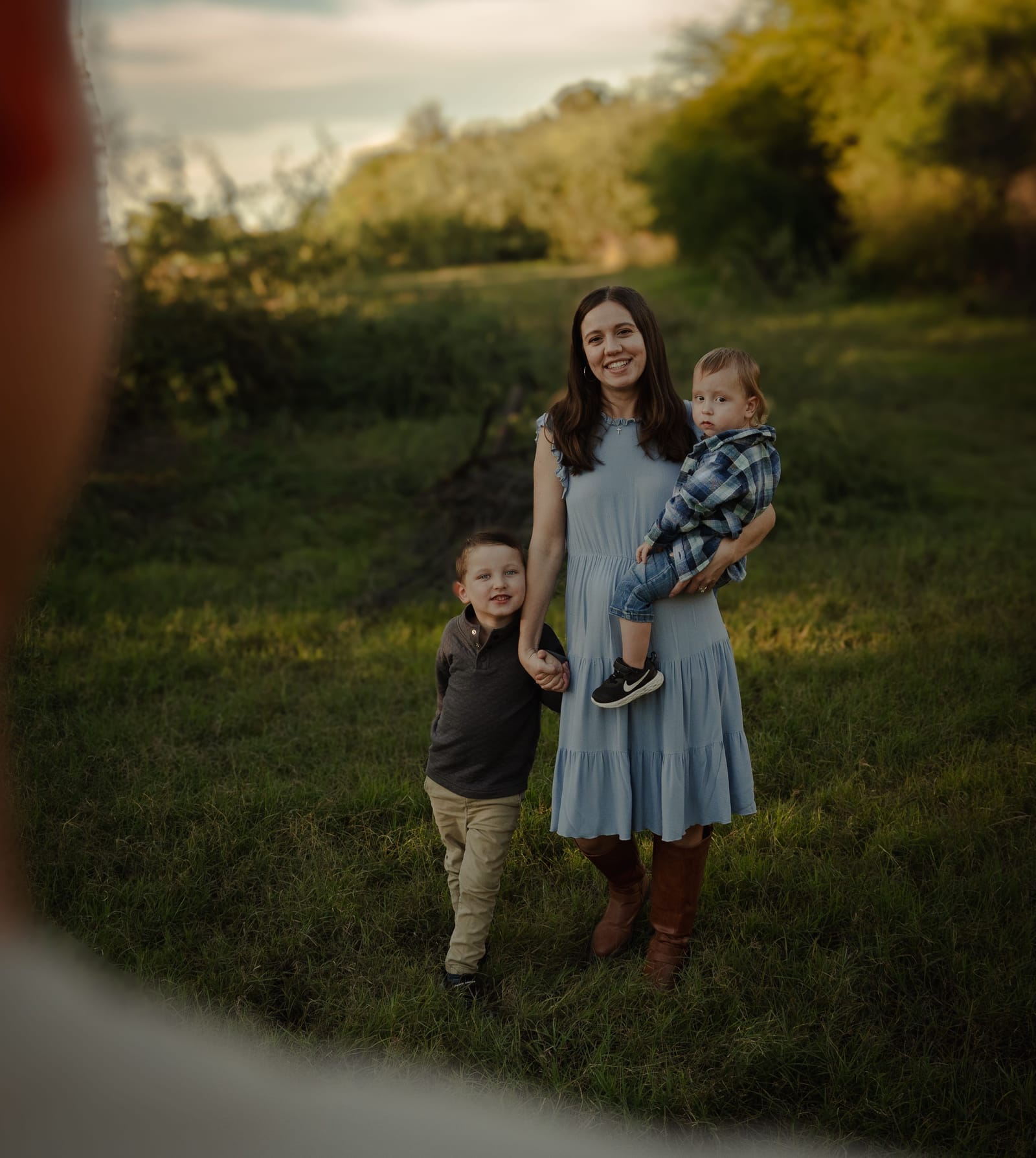 Mother carrying flowers walking with her children through a sunset field, Phoenix, Arizona