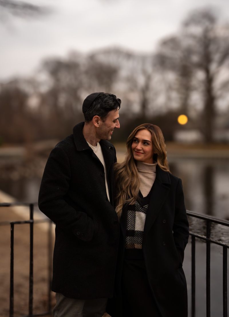 Couple portrait by lakeside railing at dusk